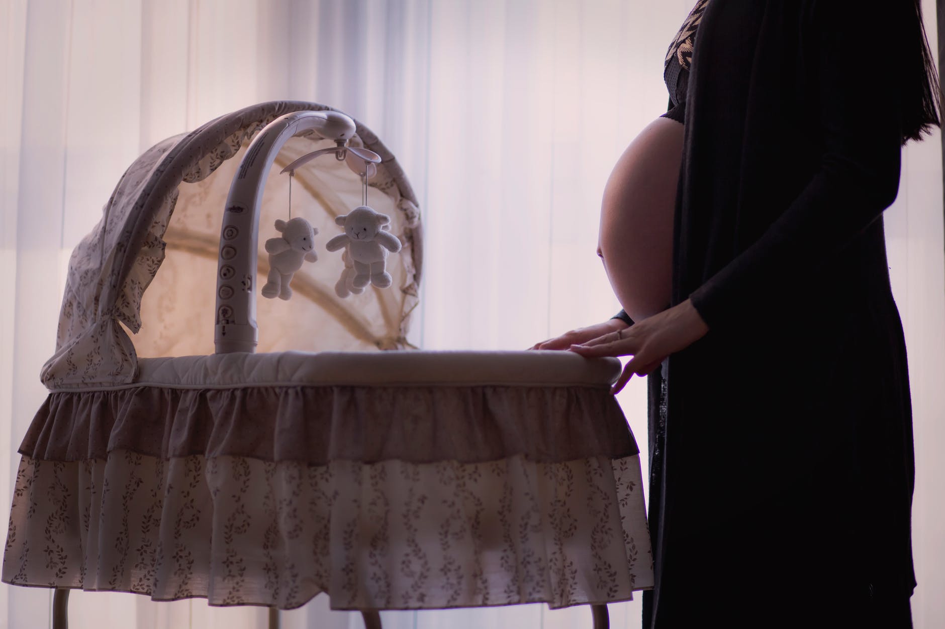 pregnant woman standing near white brown bassinet